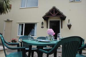StokeinteignheadPalm Tree Cottage的绿色的桌子和椅子,配有桌子和鲜花