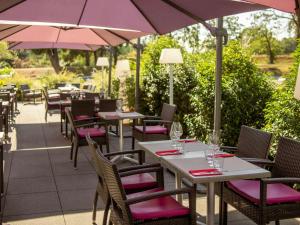 勒芒勒芒巴蒂诺尔美居酒店的室外餐厅设有桌椅和遮阳伞。