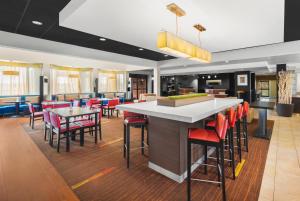 达拉斯Super 8 by Wyndham Dallas Love Field Airport的餐厅内的酒吧,配有红色的椅子和桌子