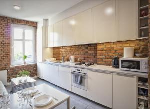 格但斯克Apartment Gdansk Wrzeszcz的厨房配有白色橱柜和砖墙