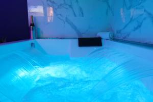 勒阿弗尔Romance spa tropical Le Havre的蓝色灯光的房间的游泳池