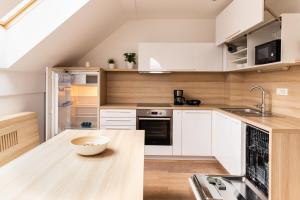 布莱德Vigorous Bled Apartment的厨房配有白色橱柜和木桌上的碗