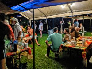 帕霍阿Kehena Mauka Nui Club LGBTQIA+ Clothing Optional的一群人坐在帐篷下的桌子上