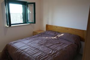 法莱尔纳Casa con 3 camere da letto LOMBARDA ALTA的一张带紫色棉被和窗户的床