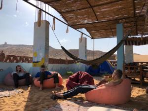 阿斯旺Nubian Kingdom Aragheed House的一群人坐在沙漠里的豆袋上