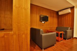 马杜赖Hotel Ramtel inn的一间设有两把椅子、一张桌子和电视的等候室