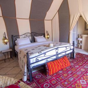 梅尔祖卡Sahara Tours luxury camp的一间卧室配有一张红色地毯的大床
