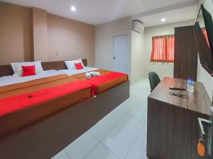 巴厘巴板RedDoorz Plus at Pelita Guest House Balikpapan的酒店客房设有一张大床和一张书桌。