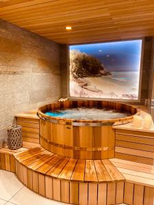 夏蒙尼-勃朗峰Chalet Pleine Vue & Spa的一个带大电视的房间,设有一个大型木制浴缸