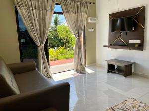 珍南海滩Laura Guest House Langkawi的带沙发、电视和窗户的客厅