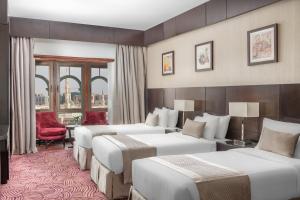 麦地那Taiba Front Hotel的酒店客房,设有四张床和红色椅子