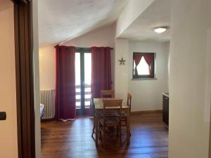 格雷索拉特里尼泰Residence Le Marmotte的一间带桌椅和红色窗帘的用餐室
