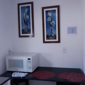 纳塔尔Natal Aconchegante的一间配有微波炉的房间和墙上的两张照片