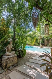 图卢姆Trece Lunas Tulum - Adults Only Enchanted Resort的花园设有一座雕像,毗邻一座游泳池