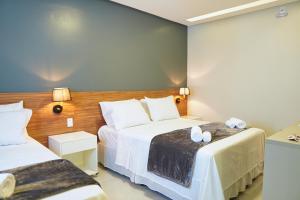 皮拉尼亚斯Pousada Encanto dos Canyons的一间卧室配有两张带白色床单的床