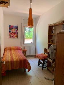 科尔百托Casa acogedora al pie de Montserrat的一间卧室设有一张床、一个窗口和一把椅子