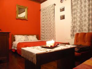Psarádes腓力酒店 的一间设有两张床的房间和一张桌子上的蜡烛