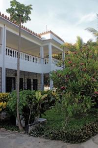 蒙巴萨图利亚背包客旅馆的一座大白色房子,有树木和灌木