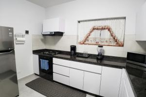 奥拉涅斯塔德Aruba Vacation House - Cozy and Modern!的厨房配有白色橱柜和黑色台面