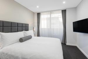 悉尼悉尼北部美利通公寓式酒店的卧室配有白色的床和平面电视。