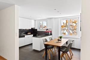 圣莫里茨Apartment Via Surpunt - Ruben- 5 Rooms的厨房配有白色橱柜和木桌及椅子