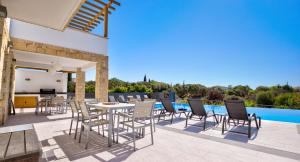 库克里亚Beautiful villa with great outside space - Meo, Aphrodite Hills Resort的游泳池旁带桌椅的天井
