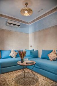 马拉喀什Riad Les Oliviers & Spa的客厅配有蓝色的沙发和桌子