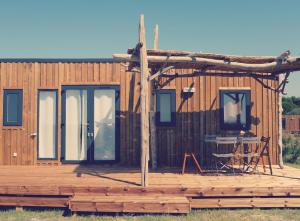 萨林德吉罗Camping Les Bois Flottés的小木屋设有门廊和甲板上的桌子
