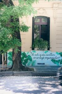 布宜诺斯艾利斯Meridiano Hostel Boutique的树旁建筑物的边标