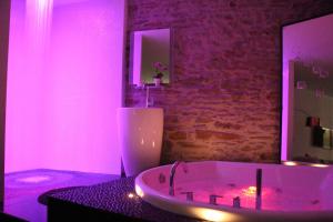 南特Le Lovt - LOVE ROOM NANTES的浴室设有粉红色灯,配有浴缸