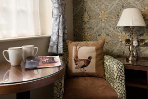 巴森斯韦特The Pheasant Inn - The Inn Collection Group的一间设有桌子和椅子的房间,上面有枕头