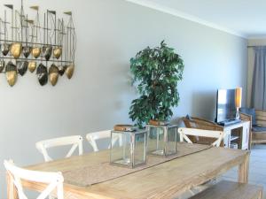 赫曼努斯Beachfront House - Hermanus Whale View的餐桌,配有白色椅子和盆栽植物