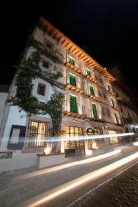 塔斯科·德·阿拉尔孔William Hotel Boutique De Diseño的白色的大建筑,晚上有绿色百叶窗