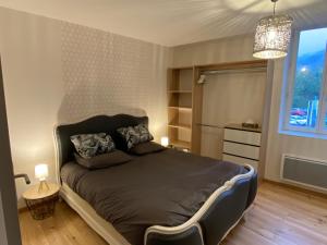 卡奥尔Cahors 62m2 - T3 neuf 4 étoiles certifié catégorie Prestige - le Bartassec - wifi - parking的一间卧室配有一张床和一个吊灯