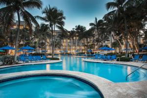 里奥格兰德Wyndham Grand Rio Mar Rainforest Beach and Golf Resort的一个带蓝色椅子的游泳池,棕榈树