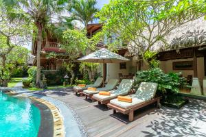 乌布Lumbung Sari Ubud Hotel - CHSE Certified的游泳池旁带椅子和遮阳伞的天井