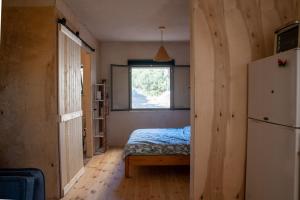 AbirimCozy Galilee Getaway的一间卧室设有一张床、一个窗口和一台冰箱