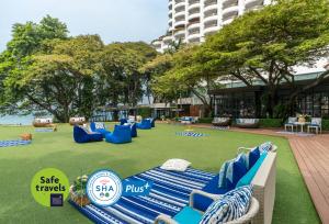 南芭堤雅Cosy Beach Hotel - SHA Extra Plus的一个大草坪上摆放着蓝色椅子