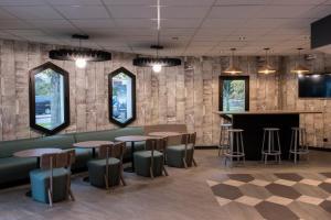 塞尔吉塞尔吉蓬图瓦兹乐港宜必思酒店的餐厅内的酒吧,设有桌子和凳子