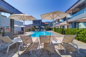 克里斯阿穆迪亚Theros Villas & Suites的游泳池旁带椅子和遮阳伞的天井