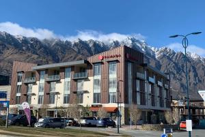 皇后镇Ramada Suites by Wyndham Queenstown Remarkables Park的酒店前方设有停车场,山底下有山。