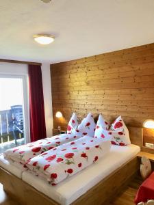 布里克森谷地霍普夫加尔滕Pension Heidelberg - Fam Fuchs的一间卧室配有一张带红色和白色枕头的大床