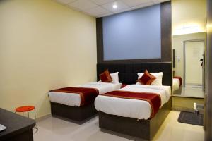瓦拉纳西HOTEL TRIDEV GRAND的配有大屏幕的酒店客房内的两张床