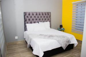 索韦托Rukza's Guest House的一间卧室配有一张大床和灰色床头板