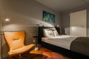 哥德堡波塞顿酒店的一间卧室配有一张床和一张橙色椅子