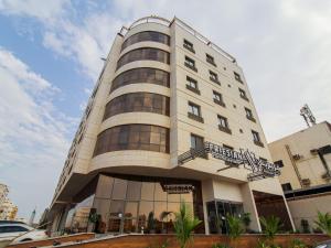 吉达Friesian Hotel Suites的一座高大的白色建筑,上面有标志