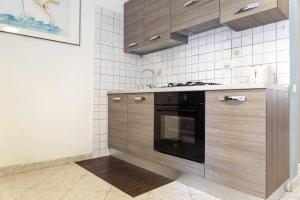 圣塔马利奈拉Santa Marinella - La Terrazza sul Mare的厨房配有木制橱柜和黑烤箱。
