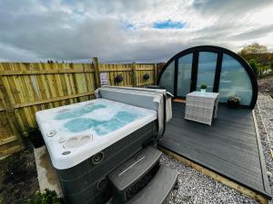 比尤利Highland Premier Glamping Pods的木甲板上的一个热水浴缸