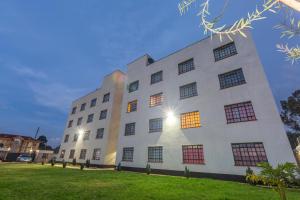 埃尔多雷特Fully furnished 1-bedroom Apartment in Eldoret的一座白色的建筑,在草地上有很多窗户