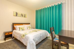 埃尔多雷特Fully furnished 1-bedroom Apartment in Eldoret的一间卧室配有一张带书桌和绿帘的床。